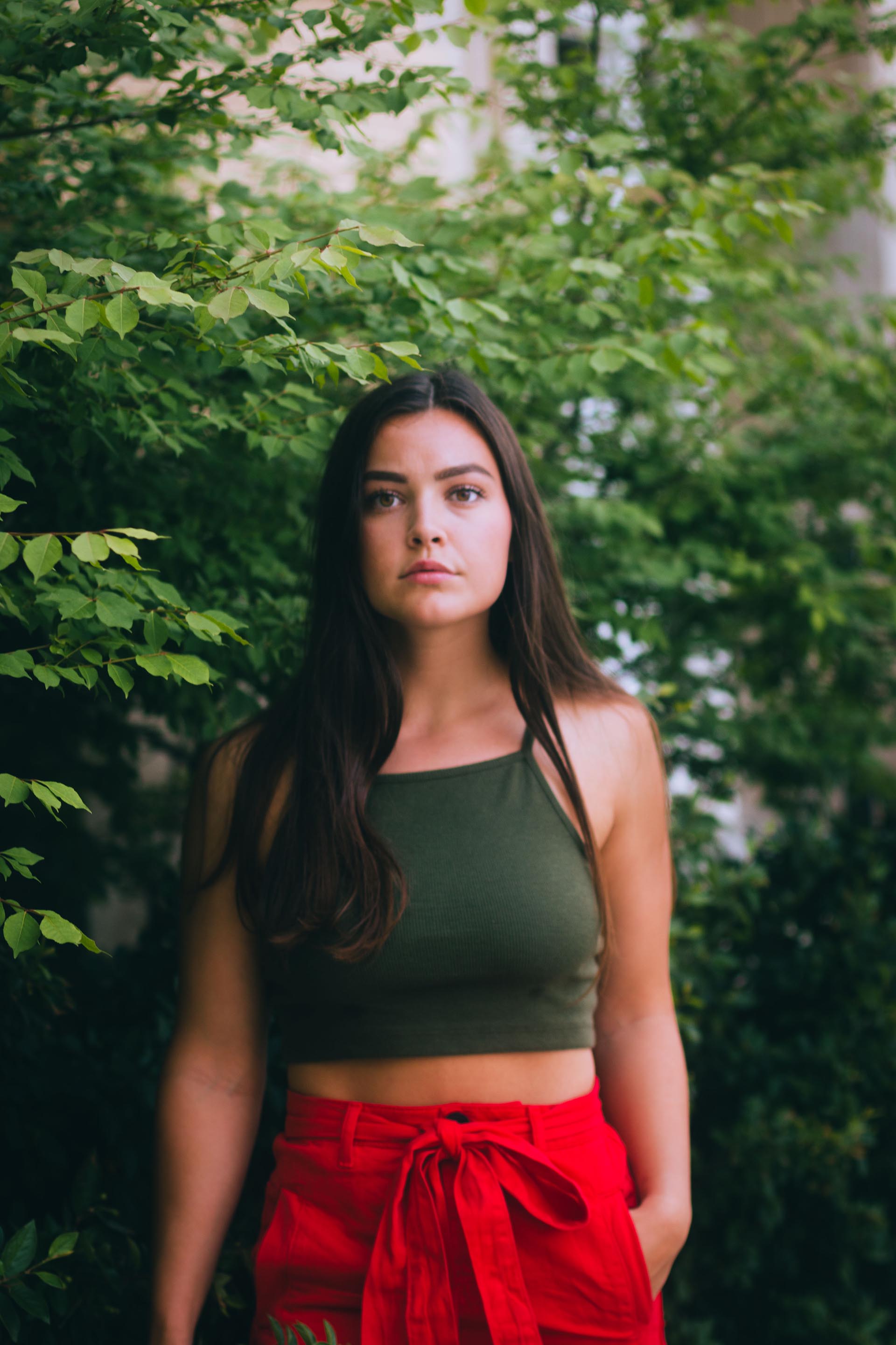 Model wearing red posing in front of green foliage